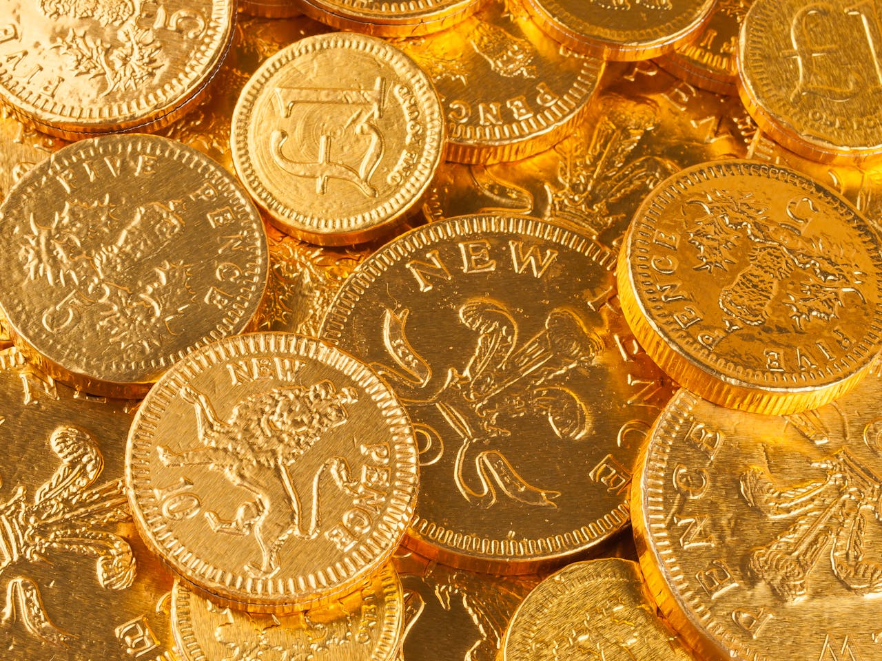 contact-img A close-up of gold-colored British pound and pence coins, showcasing intricate details.